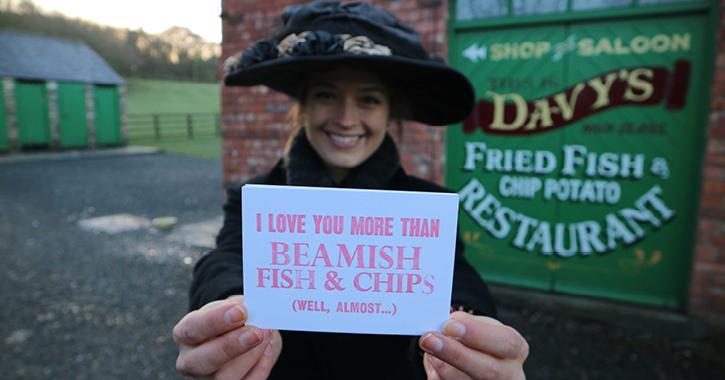 Woman dressed in 1900s costume at Beamish Museum holding a Valentine's postcard